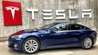 Электромобиль на фоне логотипа Tesla